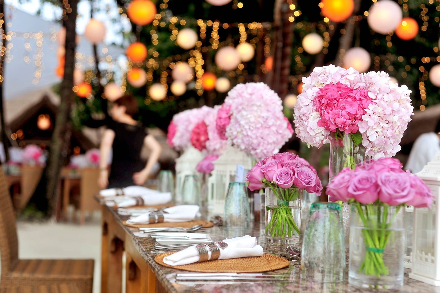 A long dinner table with low garden roses and hydrangea